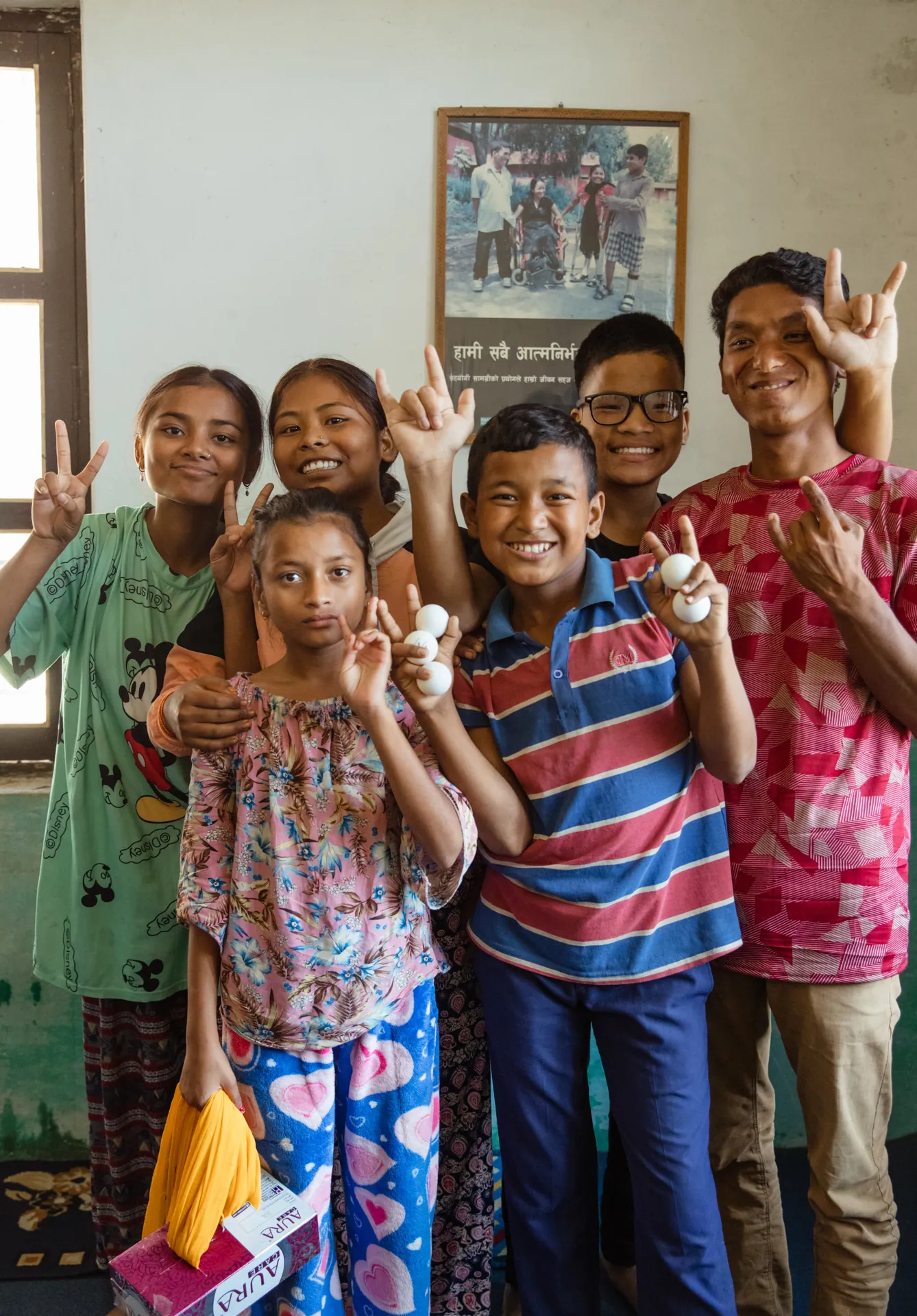 Group of smiling Deaf children at RHERI in Nepal making hand signs