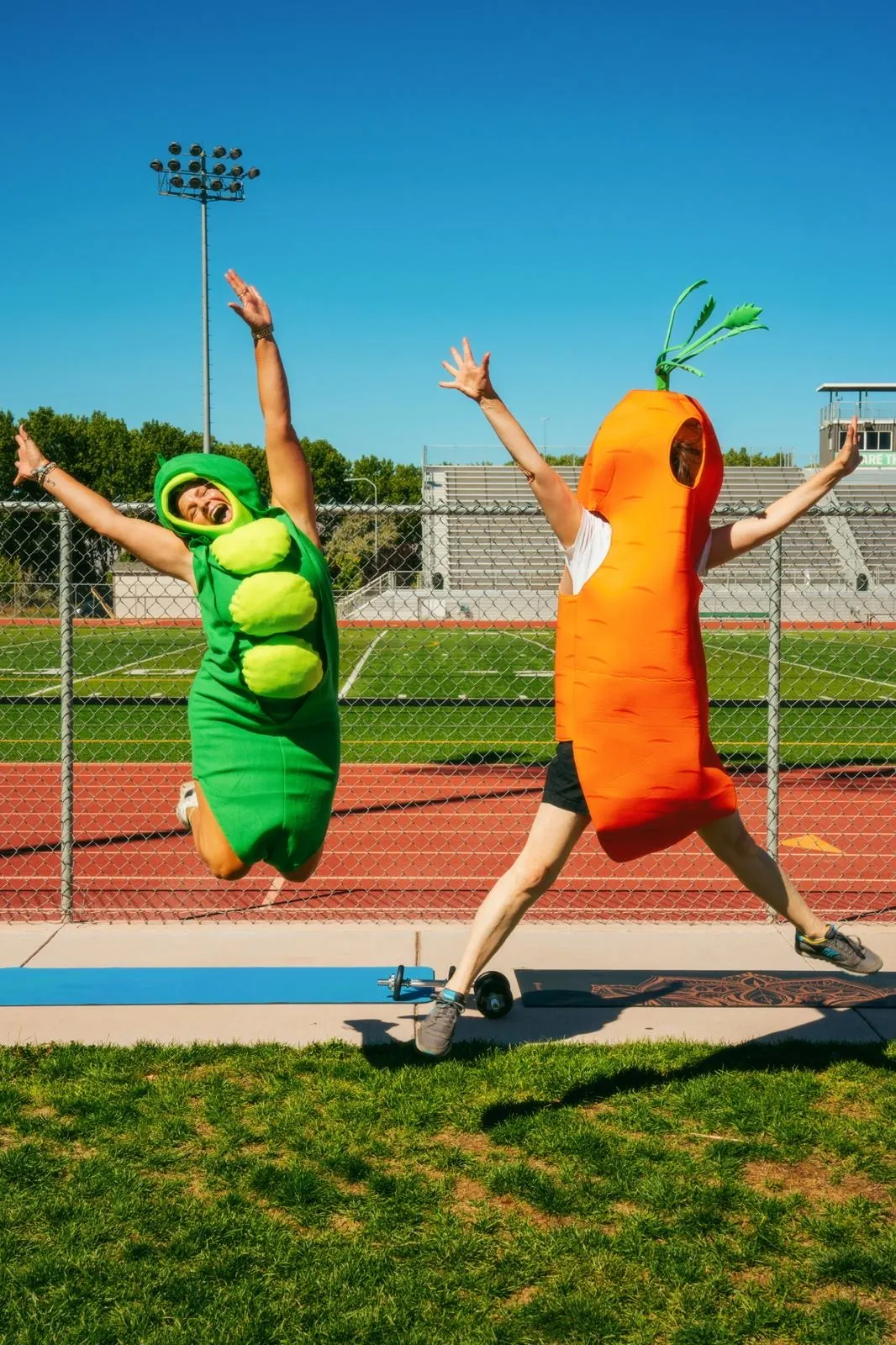 Two SafeHavens runners dressed as a pea pod and a carrot jumping on a running track