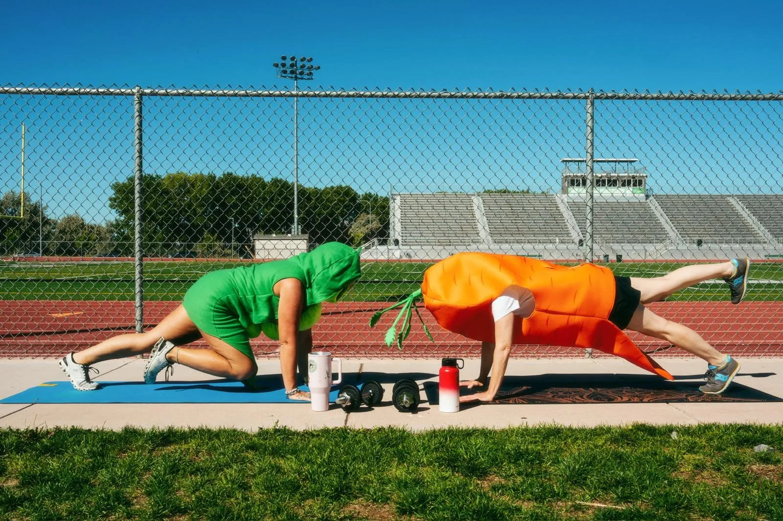 Pea pod and carrot runners doing plank exercises beside a running track