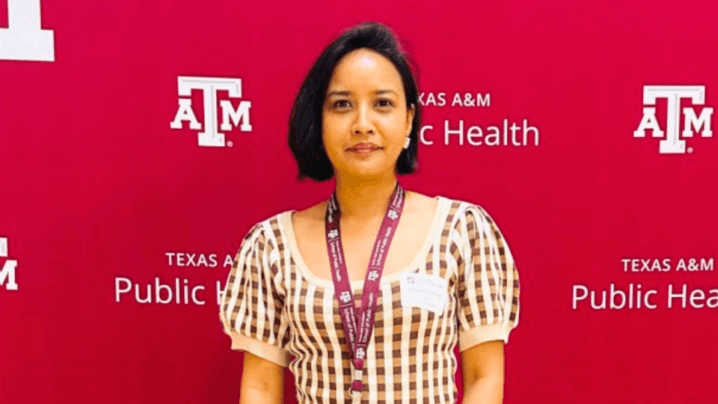 New board director Sanjeela standing in front of red background.