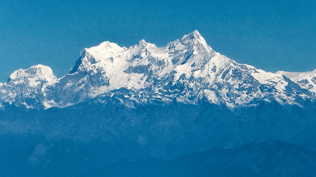 Faraway shot of Mt Everest on a blue bird day, the mountains capped with snow.